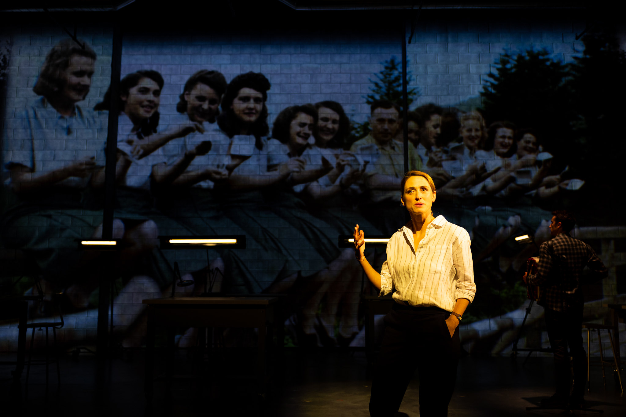 Elizabeth Stahlmann as U.S. Holocaust Memorial Museum archivist Rebecca Erbelding in “Here There Are Blueberries.” In the background is a photograph of young women employed at the Auschwitz concentration camp, relaxing and eating blueberries. (Rich Soublet II)
